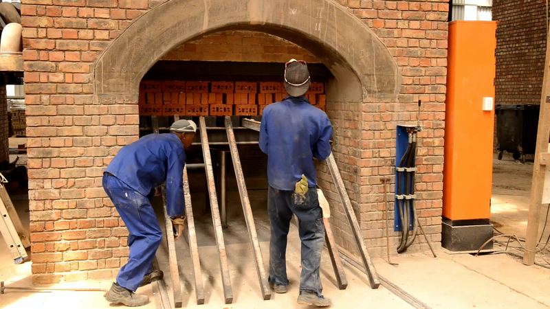 Workers unloading fired bricks from a kiln arch